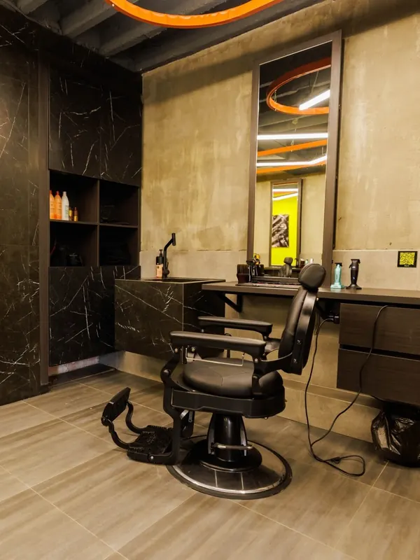 A black barber chair at its station next to the yellow wall