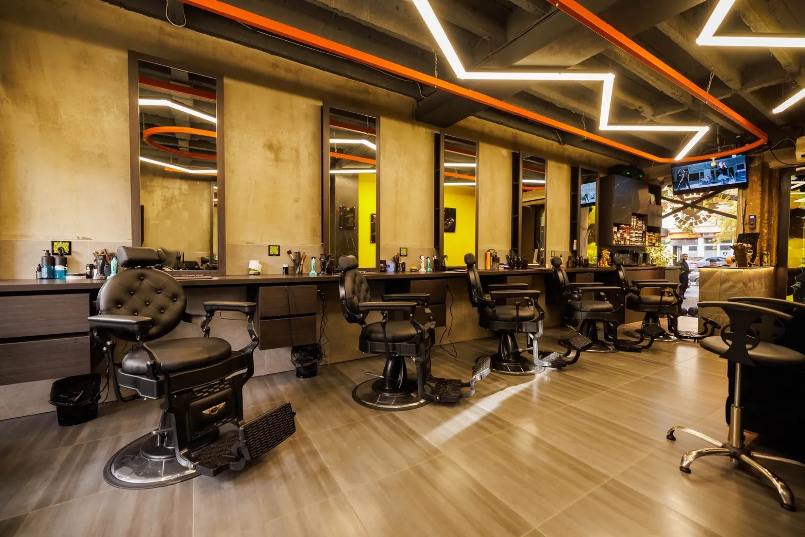 Inside Ardison: a row of black barber chairs under zig-zag neon lights