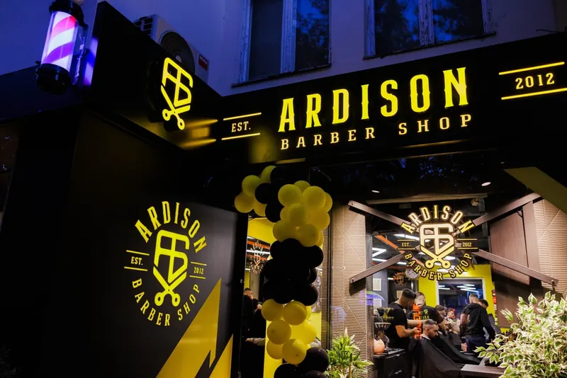 The Ardison Barber Shop front lit up in yellow at night